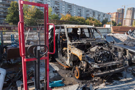 A burnt car after a fire or an accident in a parking lot covered with rust and black coal with...