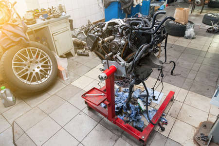 Replacement used engine mounted on a crane for installation on a car after a breakdown and repair in...