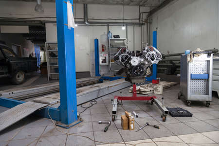 Replacement used engine mounted on a crane for installation on a car after a breakdown and repair in...