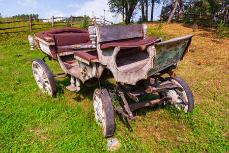 Altai, Russia - 09.25.2019: An old carriage made of wood with large wheels without a horse on a mountainside on green grass. Retro and vintage from the story.のeditorial素材
