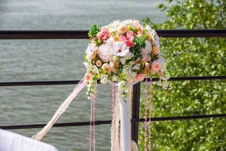 Decorative stands for decorating roses and peonies with ribbons developing in the wind on the banks of a river or ocean during a wedding ceremony.の写真素材