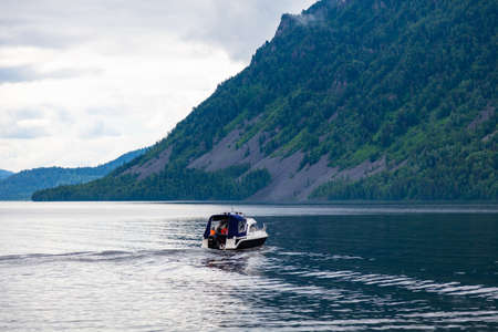 A small pleasure boat with a motor for excursions and relaxation in picturesque places on the water and traveling on a river or lake with tourists. Voyage, fishing and tourism.の写真素材