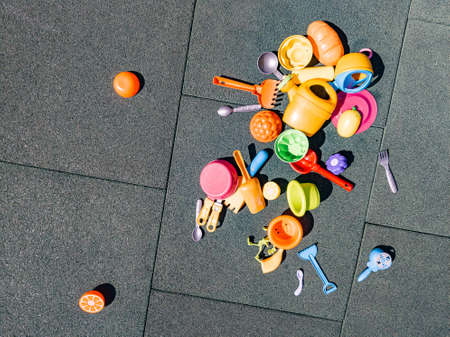 A lot of multi-colored children's toys on the playground with a rubber coating in the courtyard. Forks, spoons, rakes, scoops, plastic dishes. Childhood and carefree life, youth.の写真素材