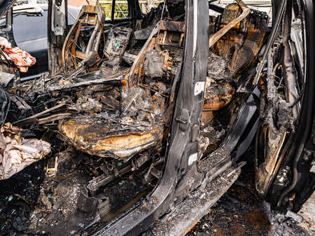 A burnt car interior after a fire or an accident in a parking lot covered with rust and black coal...