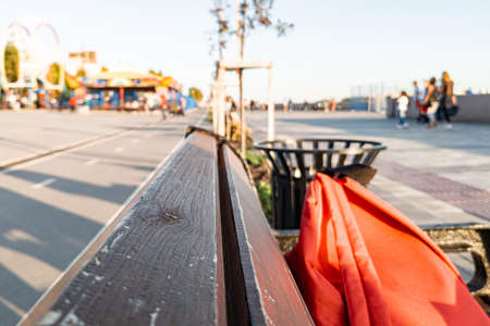 Close-up on wooden boards of a brown bench with a blurred background of a park on the promenade in...