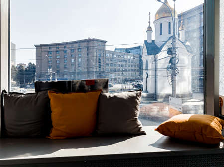 A window with a windowsill on which pillows lie with a view of the city and the attraction of a...
