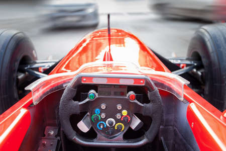 A driver driving a red Formula 1 sports car during a city race at high speed in traffic jams on the street. The spirit of competition. Extreme and adrenaline.のeditorial素材