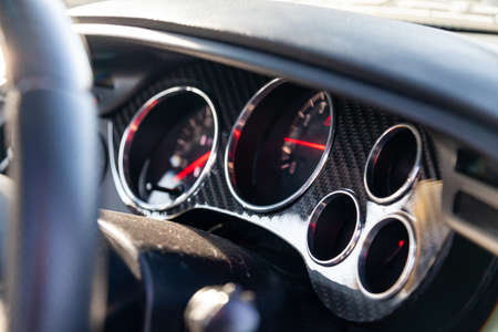 The dashboard of the car with red arrows and carbom trim, a speedometer, tachometer and other tools...
