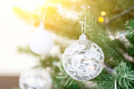 Christmas tree toy decorations of white color balls and garlands on a green coniferous tree before the new year 2020. Background for cards and congratulations.の写真素材