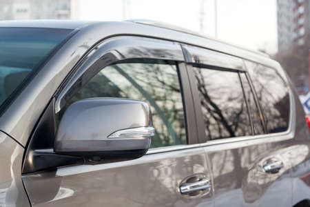 Close-up of the side left mirror with rear veiw 3d camera and window of the car body gray SUV on the parking after washing in auto service industry. Road safety while drivingの写真素材