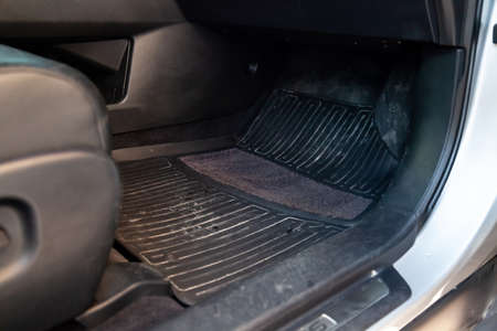Dirty car floor mats of black rubber under passenger seat in the workshop for the detailing vehicle before dry cleaning. Auto service industry. Interior of sedan.の写真素材