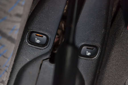 Control switch heated two front seats on car dashboard with plastic buttons to control the temperature with orange lamp of the passenger compartment and comfort while driving. Auto service industryの写真素材