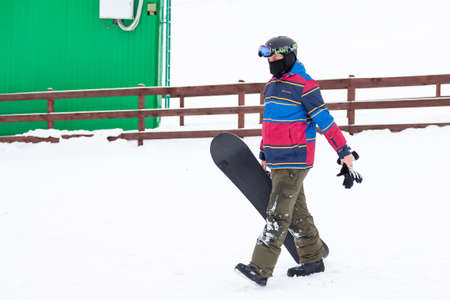 Altai, Russia - 01.01.2020: A man snowboarder going slides down the mountain over white snow in a sports tourist base Turquoise Katun. Seasonal sports.の写真素材