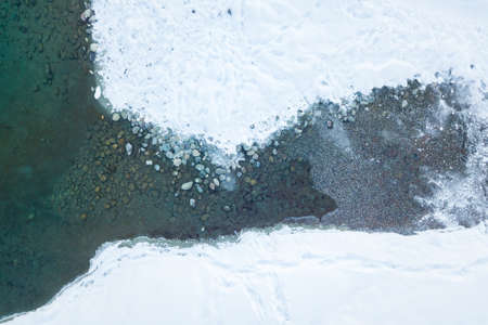 Aerial view of a blue and green lake with snow in winter in the Altai mountains in Russia. Nature...