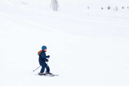 Altai, Russia - 01.01.2020: A small child skier slides down the mountain over white snow in a sports tourist base Turquoise Katun. Seasonal sports.のeditorial素材