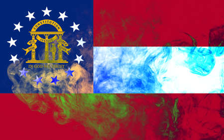 The national flag of the US state Georgia in against a gray smoke on the day of independence in different colors of blue red and yellow. Political and religious disputes, customs and delivery.の写真素材