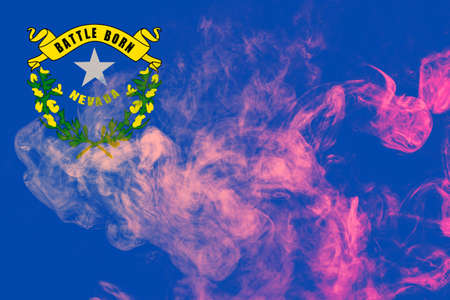 The national flag of the US state Nevada in against a gray smoke on the day of independence in different colors of blue red and yellow. Political and religious disputes, customs and delivery.の写真素材