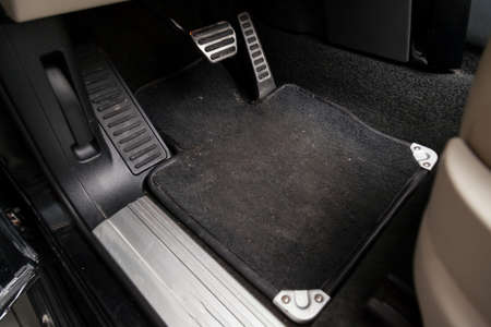 Dirty car floor mats of black carpet with gas pedals and brakes in the workshop for the detailing vehicle before dry cleaningの写真素材