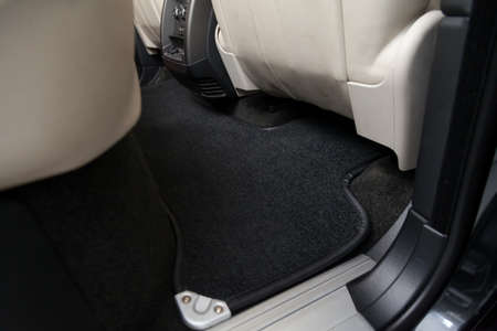 Clean car floor mats of black carpet under rear passenger seat in the workshop for the detailing...