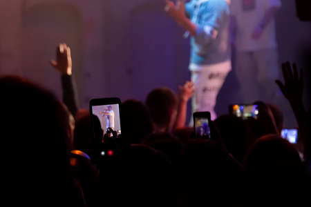 Hand with a smartphone records live music festival, Taking photo of concert stage. Party at...