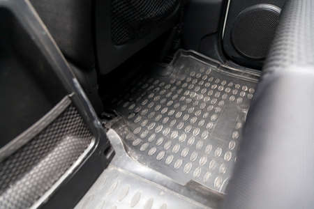 Clean car floor mats of black rubber under rear passenger seat in the workshop for the detailing...
