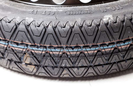 Close-up of a car spare wheel with blue and red stripes on the tread on a white background in a...