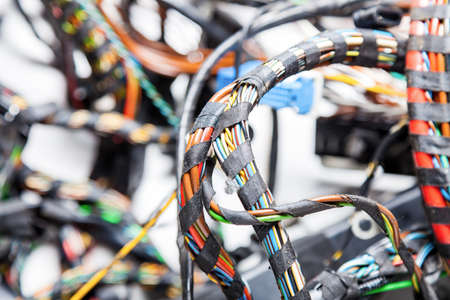 Twisted wires of red blue green yellow and orange rewound black isolation close-up on a tangled...