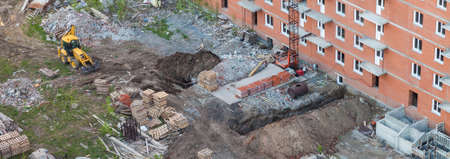 Dug out land with a yellow escalator - conducting communications to a red brick residential building...