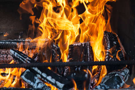Burning firewood in yellow and orange flames in mantelpiece - open fire for cooking barbecue in the country on a summer day.の写真素材