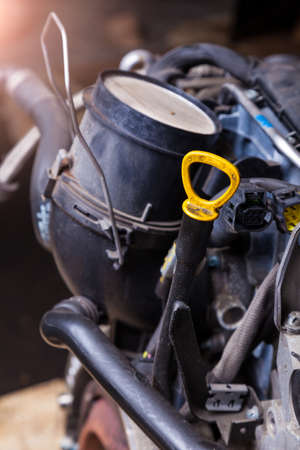 Dipstick for checking the oil level in the engine close-up with a yellow handle under the hood of...