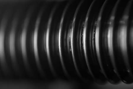 A close-up of the thread of a black bolt with whitening ribs of a spare part in an auto service as a background for publication in a thematic men's magazine.の写真素材