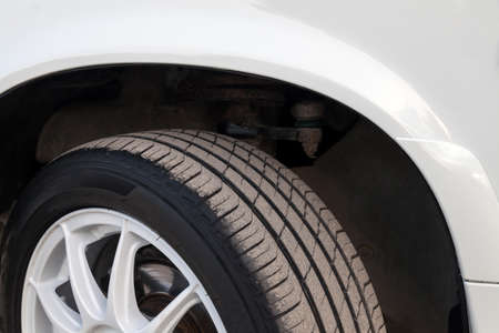 Summer black tire under the wing of a white Russian car VAZ 2114 close-up with a disk. Seasonal...
