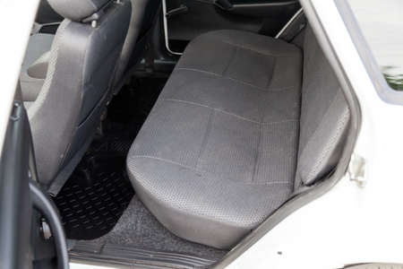 The rear row of passenger seats covered with gray cloth and with a clean rubber black rug underfoot in an old Russian car after dry cleaning prepared for sale.の写真素材