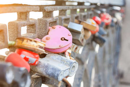 Metal fence - a fence on the city promenade with closed locks of different shapes and colors hung by the newlyweds on the wedding day according to the old tradition so that the union was strong.の写真素材