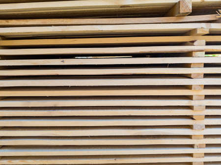 A large pile of boards sawn from trees on a sawmill for the procurement of building materials for construction. Construction industry.の写真素材