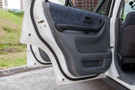 The open side doors of a white Japanese SUV in the parking lot on a summer afternoon from the inside...