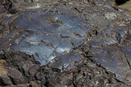Close-up of a rocky bank of a mountain river with a smooth blue rock. Background for wallpaper, post...