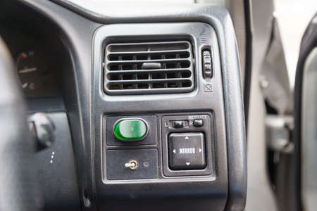 Close-up of a black plastic panel with buttons for automatically adjusting side mirrors with white markings under the air conditioning grille with air direction correction.の写真素材