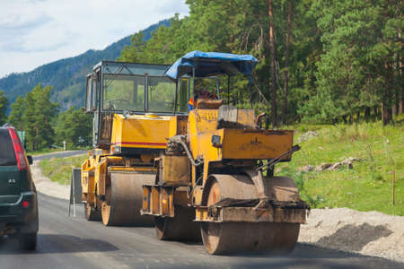 Construction machinery on the side of the road to cover asphalt - two rollers with yellow cabins at...