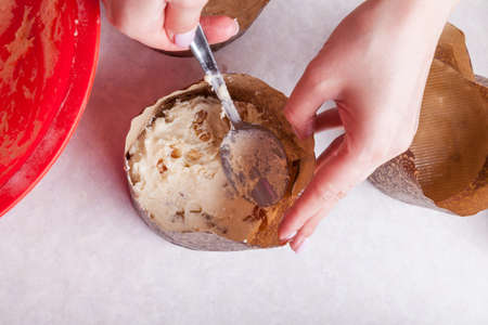Close-up of a baking dish made of brown cinnamon paper in which, using a spoon, the chef lays out...