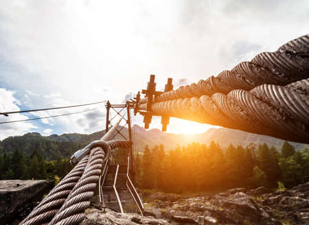 Close-up on a metal binding cable going in perspective to the bridge support with the texture of a summer sunny day. Reliability and strength concept, architecture.の写真素材