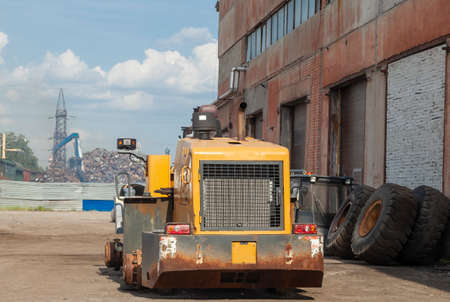 Disassembled yellow tractor without wheels and cab during repairs. Heavy construction equipment.