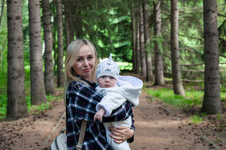 Beautiful mother with a child in the autumn forest, a mother with her son on a walk, a woman blonde with long hairの写真素材