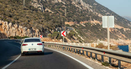 Kas, Turkey - 08.25.2021: White VW Passat on a highway in Kas, Turkey. VW Passat is a sedan produced by VW. Driving by the coastline near the mountains.のeditorial素材