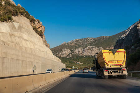 Rear view of truck on the mountain road, between rocks on a summer. Semi-trailer carrying goods on highway in turkey. Cargo transportation concept.の写真素材