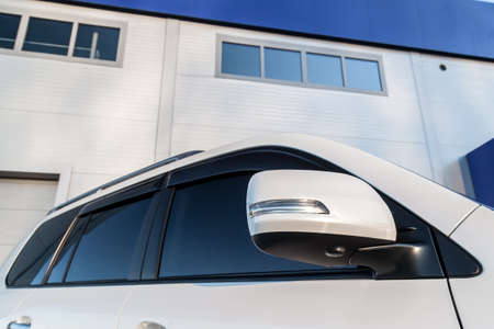 Rear-view mirror or door mirror closed for safety at car park, Side mirror of gray car black tinted glassの写真素材