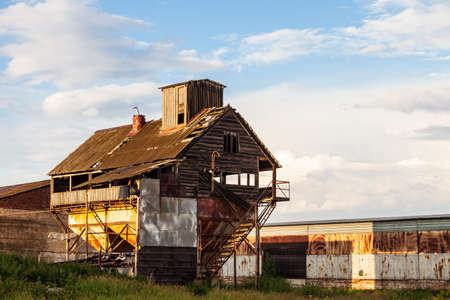 Old abandoned agricultural building with rusty iron walls. Soviet and Russian rural.