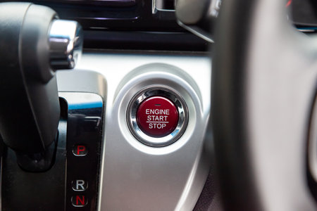 Red Button start and turn off the ignition of the car engine close-up on the dashboard, electric...