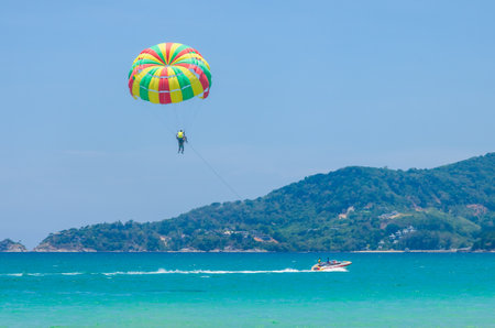 Beautiful Patong beach in Phuket, Thailand with colorful parachute white sand, turquoise water and palm treesの写真素材