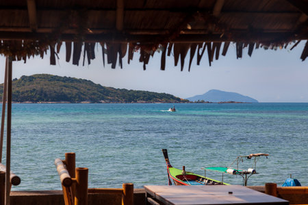 restaurant on the waterfront of rawai beach in thailand overlooking the sea with old boat floatingの写真素材